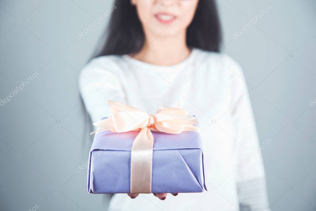 woman hand holding gift box on gray background