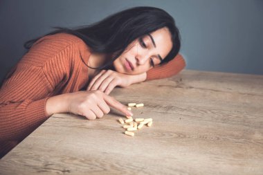 Üzgün kadın ve masanın arkasında haplar.