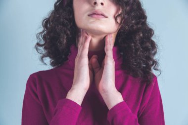 Gri arka planda boğazı ağrıyan bir adam.