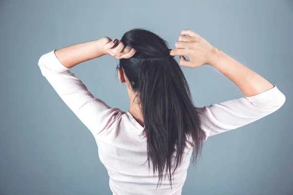 woman tie the hair on the gray background