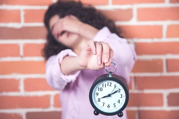 sad woman hand clock on brick wall background