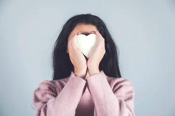 woman hand holding heart in face background