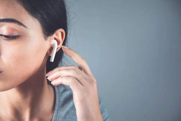 woman ear white earphone on the gray background