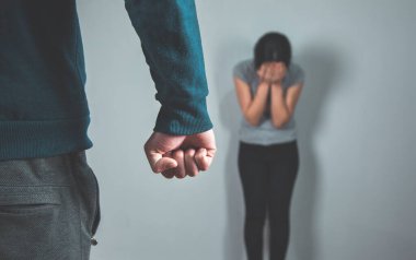 Kızgın adam yumruğu ve gri arka planda üzgün kadın.