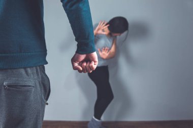 Kızgın adam yumruğu ve gri arka planda üzgün kadın.