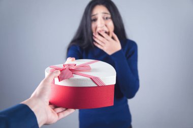 Şaşırmış bir kadın ve erkek eli kırmızı kalp kutusu.