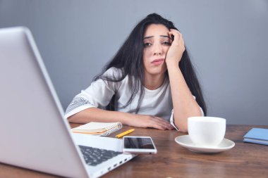 Masasında kahve ve bilgisayar olan üzgün kadın cep telefonu.