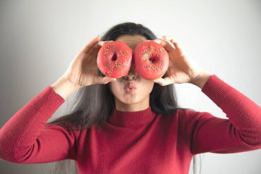 Mutlu kadın Gri arka planda donut 'ı gözüne kestirdi