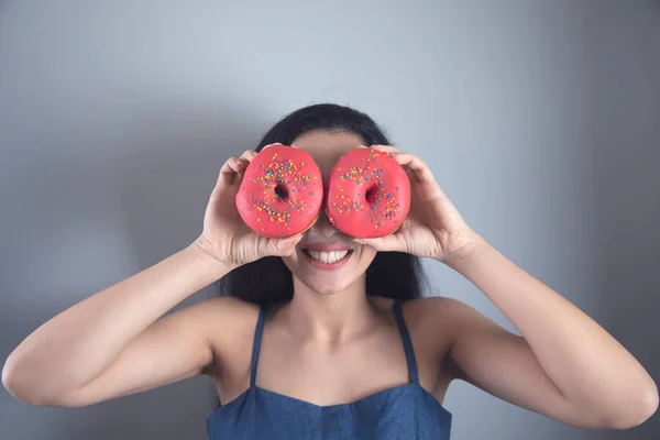 stock image happy woman hand Donut in eye on grey background