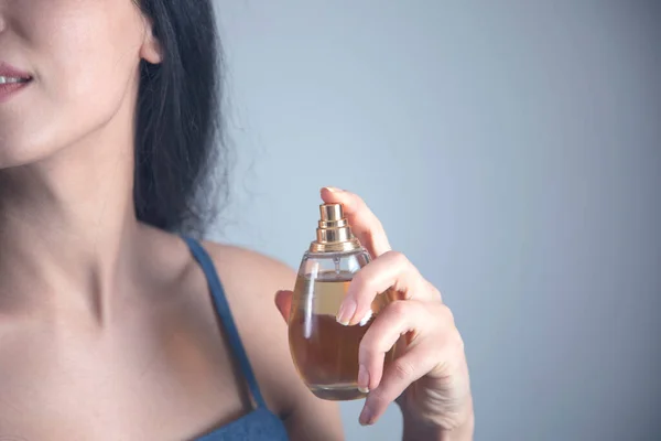 woman hand holding perfume bottle on grey background