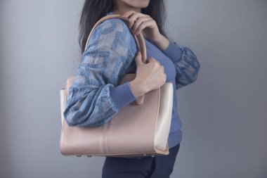 Gri arka planda pembe çanta tutan kadın.