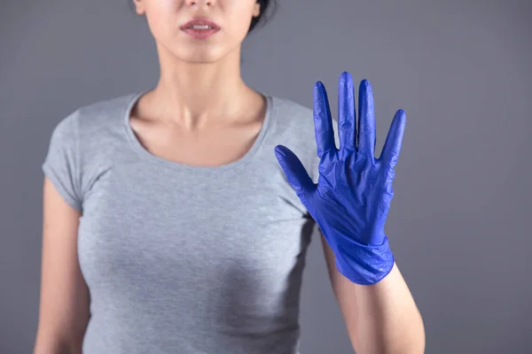 Γυναίκα Χέρι Μπλε Γάντι Και Πινακίδα Στοπ Γκρι Φόντο — Φωτογραφία Αρχείου