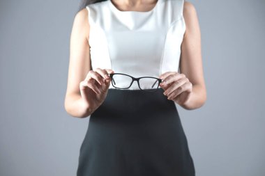 Genç iş kadını. Gri arka planda el gözlüğü.