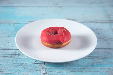 Mavi ahşap masada beyaz tabakta çörek.
