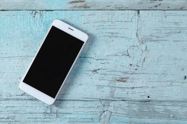 Akıllı telefon mavi ahşap masada.