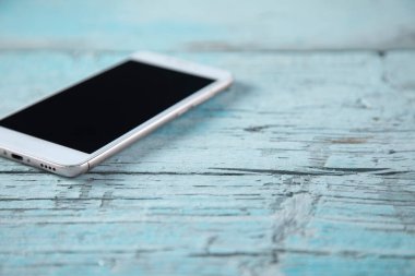 Akıllı telefon mavi ahşap masada.