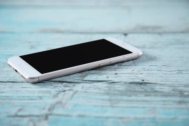 Akıllı telefon mavi ahşap masada.