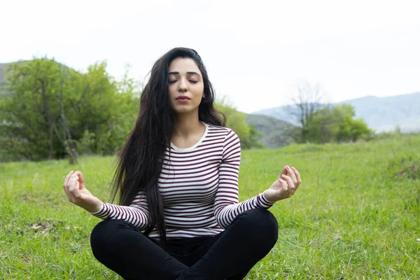 meditating woman sitting in green grass background