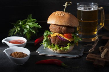 Büyük Hamburger ve Lager bira siyah ahşap arka plan üzerinde. Rusti'yi