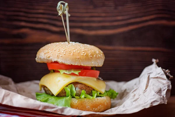 Hamburger op kraftpapier op een houten achtergrond — Stockfoto