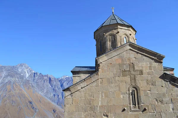 Gergeti Kilisesi mavi gökyüzüne karşı dağlarda kayboldu. Georgia mı? Kazbegi