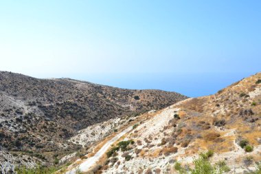 Güneşli bir günde mavi gökyüzünün altındaki dağların arasında yol. Kıbrıs.