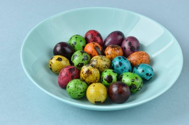 Mavi arka planda boyanmış yumurtalar. Tabakta bıldırcın yumurtası.