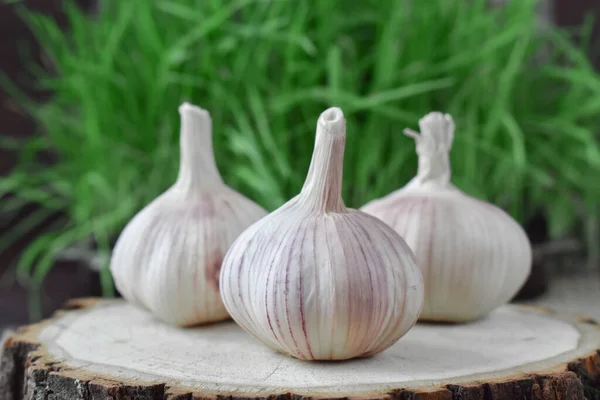 Drei Knoblauchköpfe Auf Einem Holzständer Gras — Stockfoto