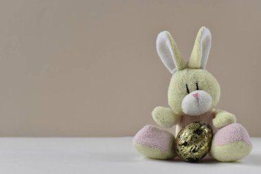 Paskalya yumurtalarıyla sarılmış Paskalya tavşanı. Paskalya yumurtalarıyla sarılmış Paskalya tavşanı. Bej bir arka planda yakın plan yumurtaları olan, uzayın kopyası olan sevimli küçük bir tavşan..