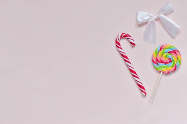 İki şeker ve arka planda beyaz bir fiyonk. Kartpostal Doğum günü tatlı karamel. Burası boş bir yer. Üst Görünüm Düz Düzen