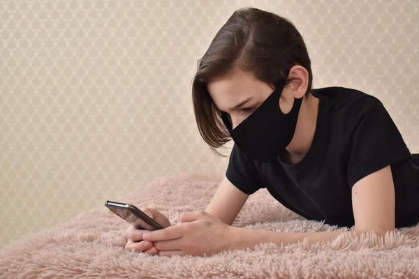 Αγόρι Ξαπλώνει Μαύρα Ρούχα Στο Κρεβάτι Ένα Τηλέφωνο Καραντίνα Του — Φωτογραφία Αρχείου