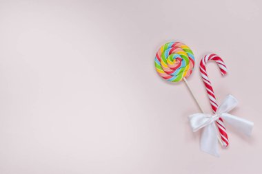 Sağ tarafta farklı şekillerde iki parlak renkli tatlı ve bir fiyonk var..