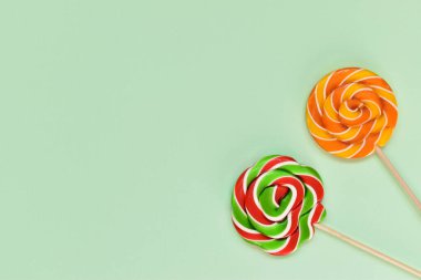 Yeşil arka planda tahta bir çubuğun üzerinde bir çift lolipop. Kartpostal Doğum günü. Burası boş bir yer. Üst Görünüm Düz Düzen