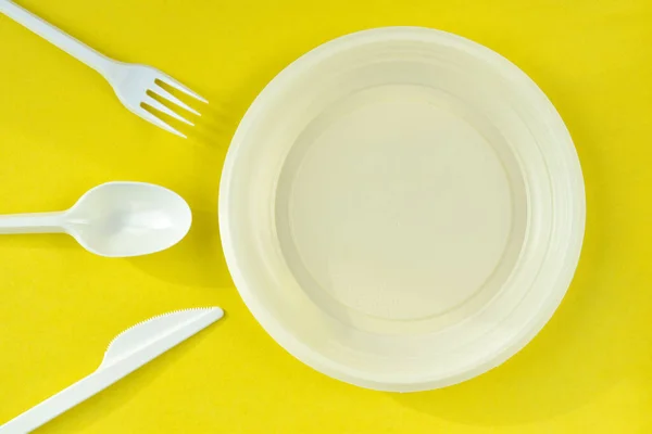 Única vez utensílios de plástico branco sobre um fundo amarelo — Fotografia de Stock