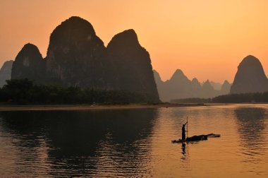 Yangshuo 'daki balıkçıların silueti, Li nehrinde gün batımı. Yangshuo, Guilin Guangxi Çin yakınlarında popüler bir turistik bölge ve şehirdir..