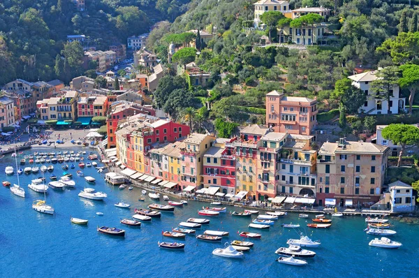 Liguria Portofino, vista del puerto con barcos amarrados y casas de colores pastel que bordean la bahía con árboles en las colinas detrás, Italia . — Foto de Stock