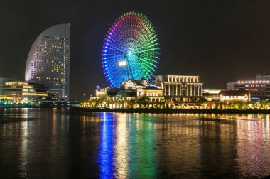 Yokohama, Japonya 'nın Minato Mirai 21 bölgesindeki Shinko bölgesinin aydınlatılmış gece manzarası. Cosmo World lunaparkı da dahil..