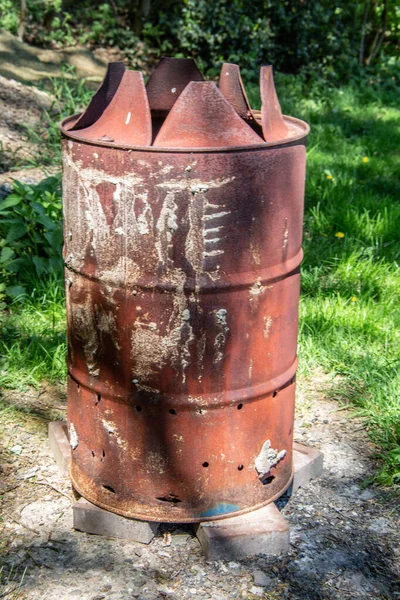 old rusty oil barrel as fireplace on meadow