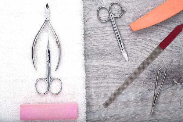 Manicure or pedicure set tools are placed on a table with a white towel in the beauty salon. Equipment for beauty shop or beauty parlour. Set for home manicure and nail care.