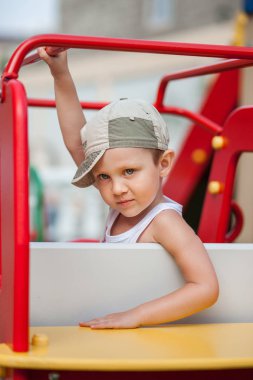 little boy in a cap plays in the playground