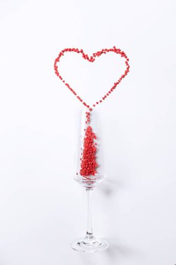 heart shaped candies spilled out of the glass on a white background