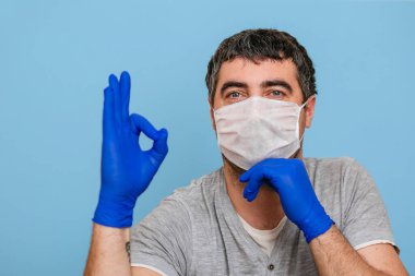 Tıbbi maskeli ve mavi eldivenli bir adam.. 