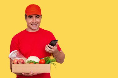 Üniformalı bir kurye, içinde yiyecek olan karton bir kutu tutuyor. Servis karantina pandemik koronavirüsü. 