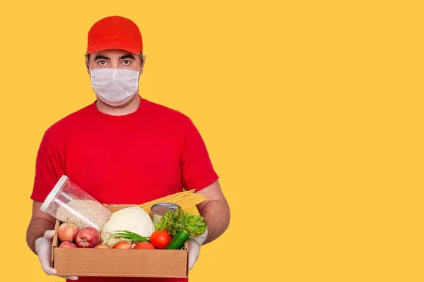 Кур'єрський працівник у формі тримає картонну коробку з їжею ізольовано. Служба карантину пандемії коронавірусу . — стокове фото