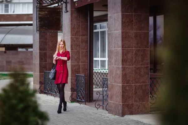 Young beautiful blonde in a red dress in the city. A business woman goes to work. Female businessman. — Stock Photo, Image