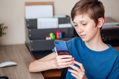 Genç bir çocuk cep telefonuyla arkadaşlarına, sınıf arkadaşlarına ve akrabalarına video araması yapıyor. Haberleri neşeyle paylaşıyoruz.