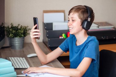 Genç bir çocuk cep telefonuyla arkadaşlarına, sınıf arkadaşlarına ve akrabalarına video araması yapıyor. Haberleri neşeyle paylaşıyoruz.