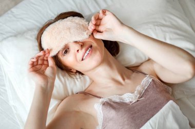 Yukarıdan, sağlıklı bir genç kadının gülüşünü, iyi bir dinlenmeden sonra uyku maskesini çıkarışını görmek kaydedilir. Mutlu kızıl saçlı bir bayan enerjik hissediyor, sabahın erken saatlerinde enerji dolu..