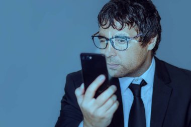 Yüz tanıma. Biyometrik doğrulama. Yeni yüz tanıma teknolojisi kavramı takım elbiseli genç bir iş adamı elinde akıllı bir telefonla. Kavram: DNA sistemi, bilim ve teknoloji.