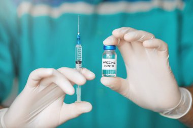 Doktor, hemşire, bilim adamı elinde grip, kızamık, koronavirüs, covid-19 hastalığı aşısı olan mavi eldivenleri teslim etti. 